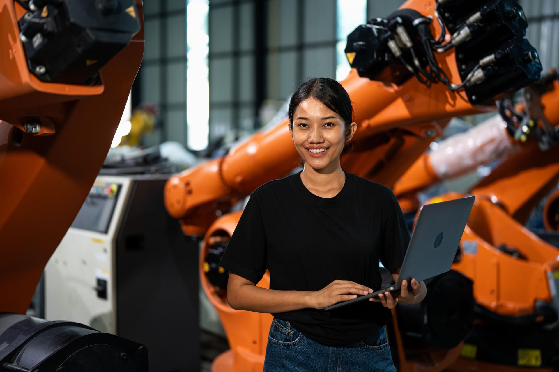 Female engineer using laptop to analyze robotic systems